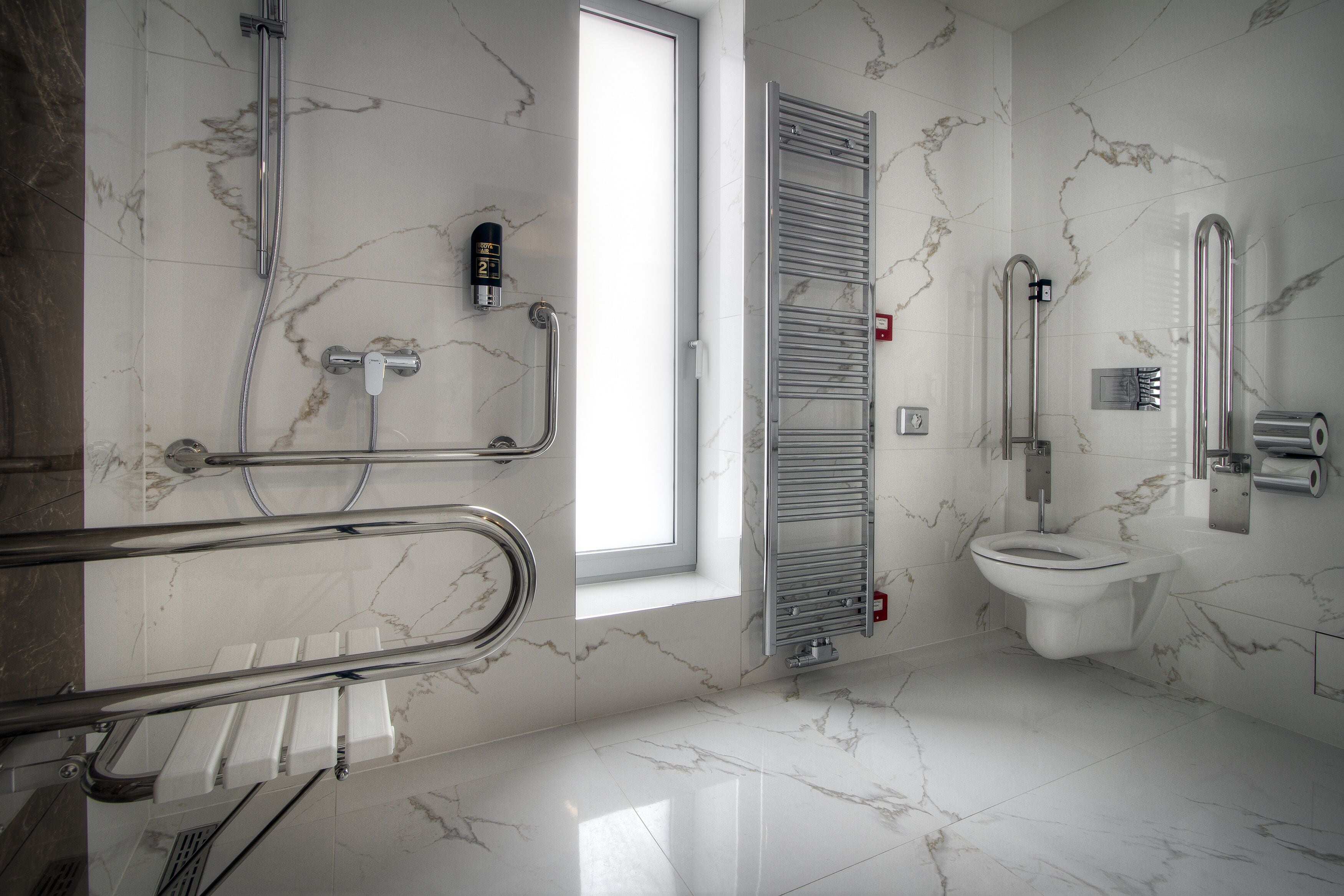 Een moderne badkamer met een douche, toilet en handgrepen.