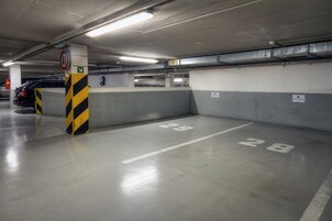A parking garage with concrete walls, marked parking spots, and a directional sign.