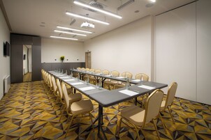 A conference room with a long table, chairs, and a patterned carpet.
