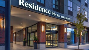 The exterior of a Marriott Residence Inn with a brick facade, large glass doors, and a well-lit entrance.
