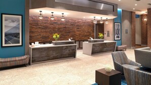 A modern reception area with a stone wall backdrop, a reception desk, seating, and a large mirror.