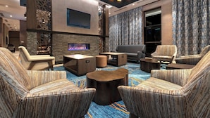 A modern lounge area with striped upholstered chairs, a central coffee table, and a flat-screen TV mounted on the wall.