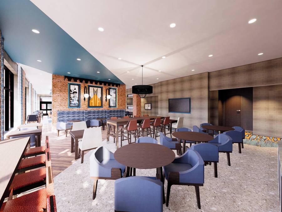A modern lounge area with seating arrangements, a brick accent wall, and a large screen.