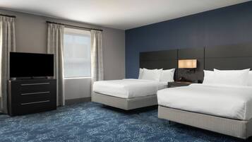 A hotel room with two beds, a TV, a dresser, and a window with curtains.