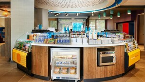 Una estación de bebidas de autoservicio con un mostrador refrigerado y una máquina de café.