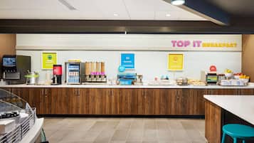 A breakfast area with a counter, coffee machines, and various food items.