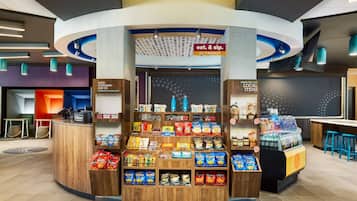 Un kiosque ouvert 24 heures sur 24, 7 jours sur 7, proposant des collations et des boissons, une caisse enregistreuse et une enseigne indiquant les produits locaux.