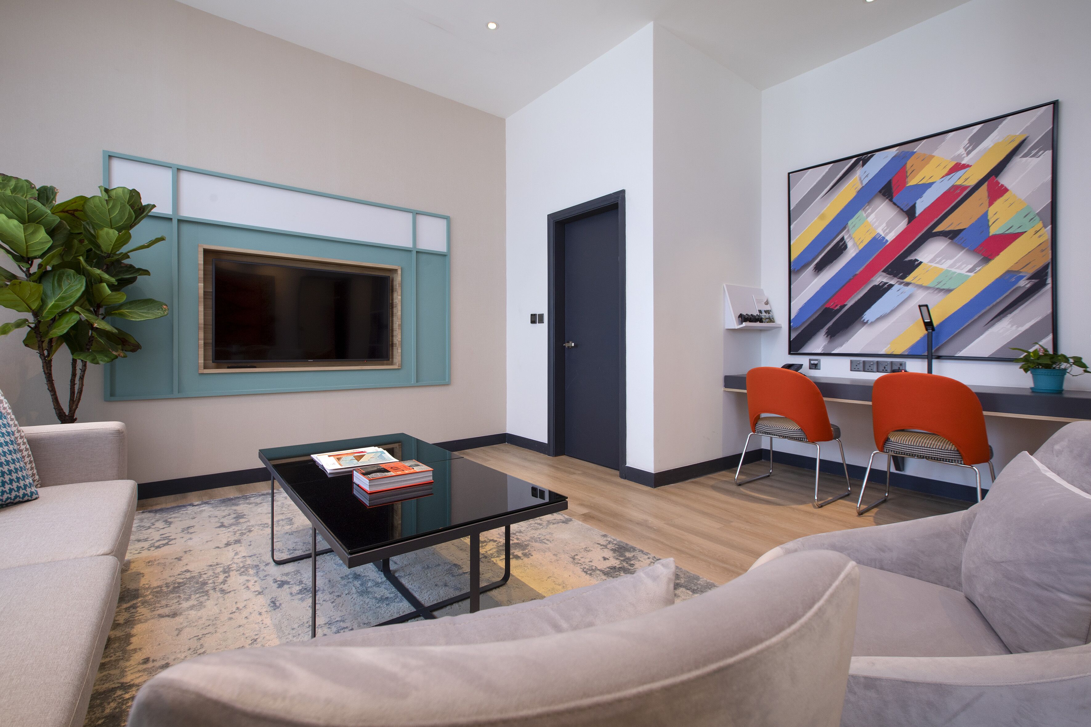 A modern living room with a sofa, a coffee table, and two orange chairs.