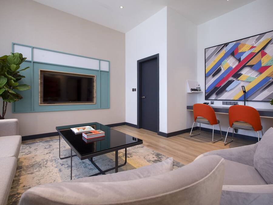 A modern living room with a sofa, a coffee table, and two orange chairs.
