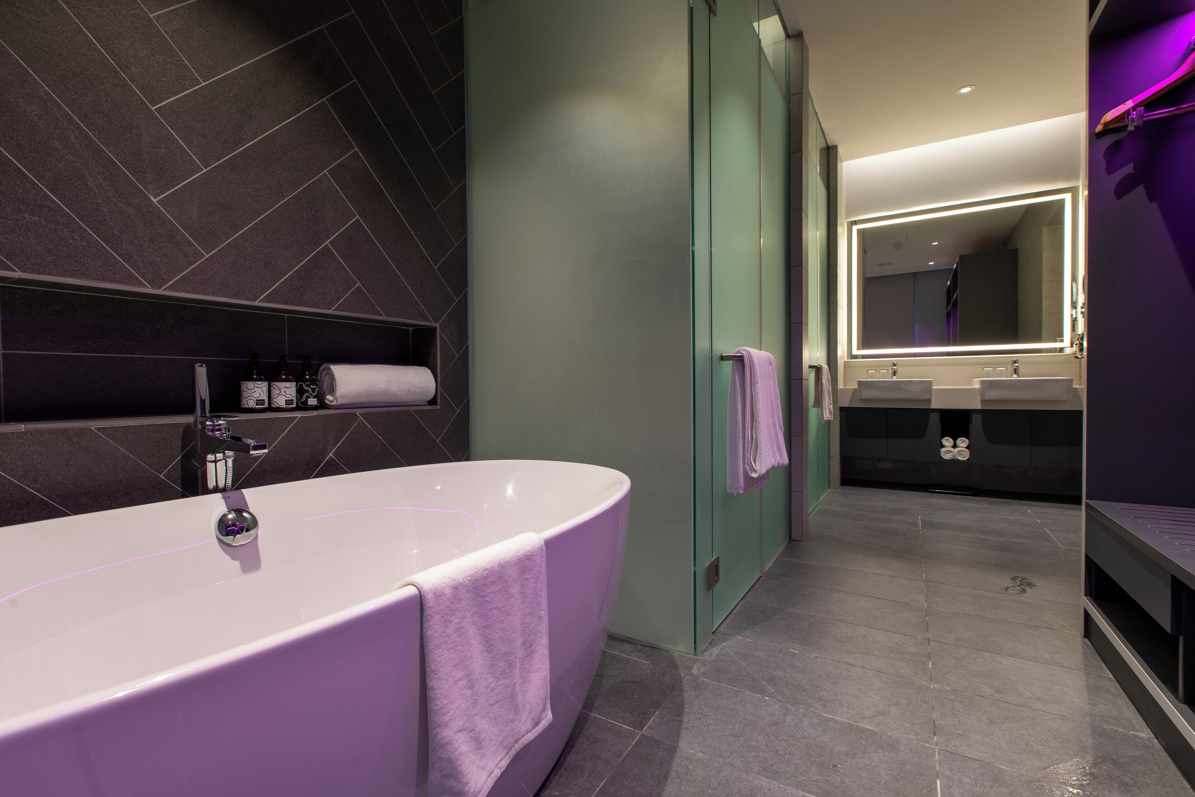 Une salle de bain moderne avec une baignoire sur pieds, une douche à parois de verre et un meuble-lavabo doté de deux vasques.