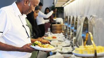 A buffet setup with various food items and a person serving food.