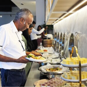 A buffet setup with various food items and a person serving food. -  INNSiDE by Meliá Kuala Lumpur Cheras (Kuala Lumpur)