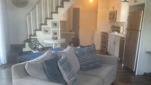 Un salon comprenant un canapé, une table à manger et un escalier menant à la cuisine.