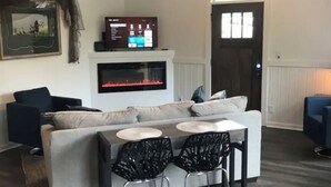 Un salon comprenant un canapé, une cheminée, un téléviseur et un coin repas avec des chaises.