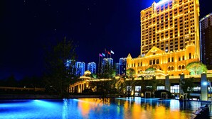 A large hotel with multiple floors, a swimming pool, and a bridge in the foreground. - Wyndham Grand Kunming East (Kunming)