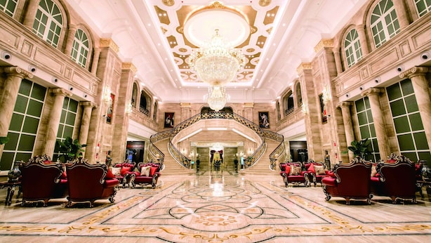 A grand lobby with a large chandelier, ornate columns, and red upholstered seating. - Wyndham Grand Kunming East (Kunming)