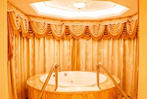 Um banheiro luxuoso com uma banheira de pé, cortinas elaboradas e um claraboia.