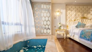 A bedroom with a large bed, a nightstand, a decorative wall, and a blue tiled area with white flowers. - Wyndham Grand Kunming East (Kunming)