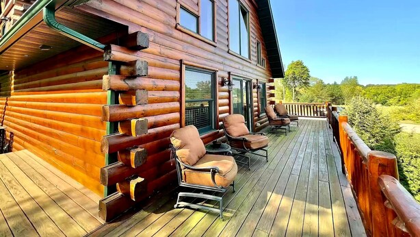 Un chalet en bois avec une terrasse, un espace salon extérieur et une vue panoramique.