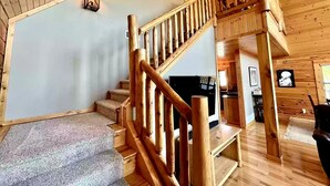 Un intérieur en bois avec un escalier, un téléviseur à écran plat et un coin cuisine.