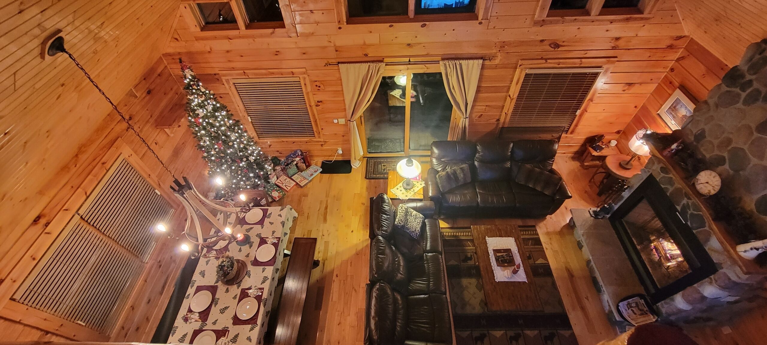 Interior acogedor de una cabaña con comedor, chimenea y un árbol de Navidad.