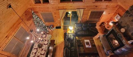 Interior acogedor de una cabaña con comedor, chimenea y un árbol de Navidad.