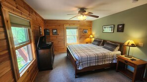 A wooden cabin bedroom with a bed, a desk, a ceiling fan, and framed pictures on the walls. - Devil’s Lake 5BR Cabin w/ Fireplaces,King beds,Skiing* Near Water parks in Dells (Baraboo)