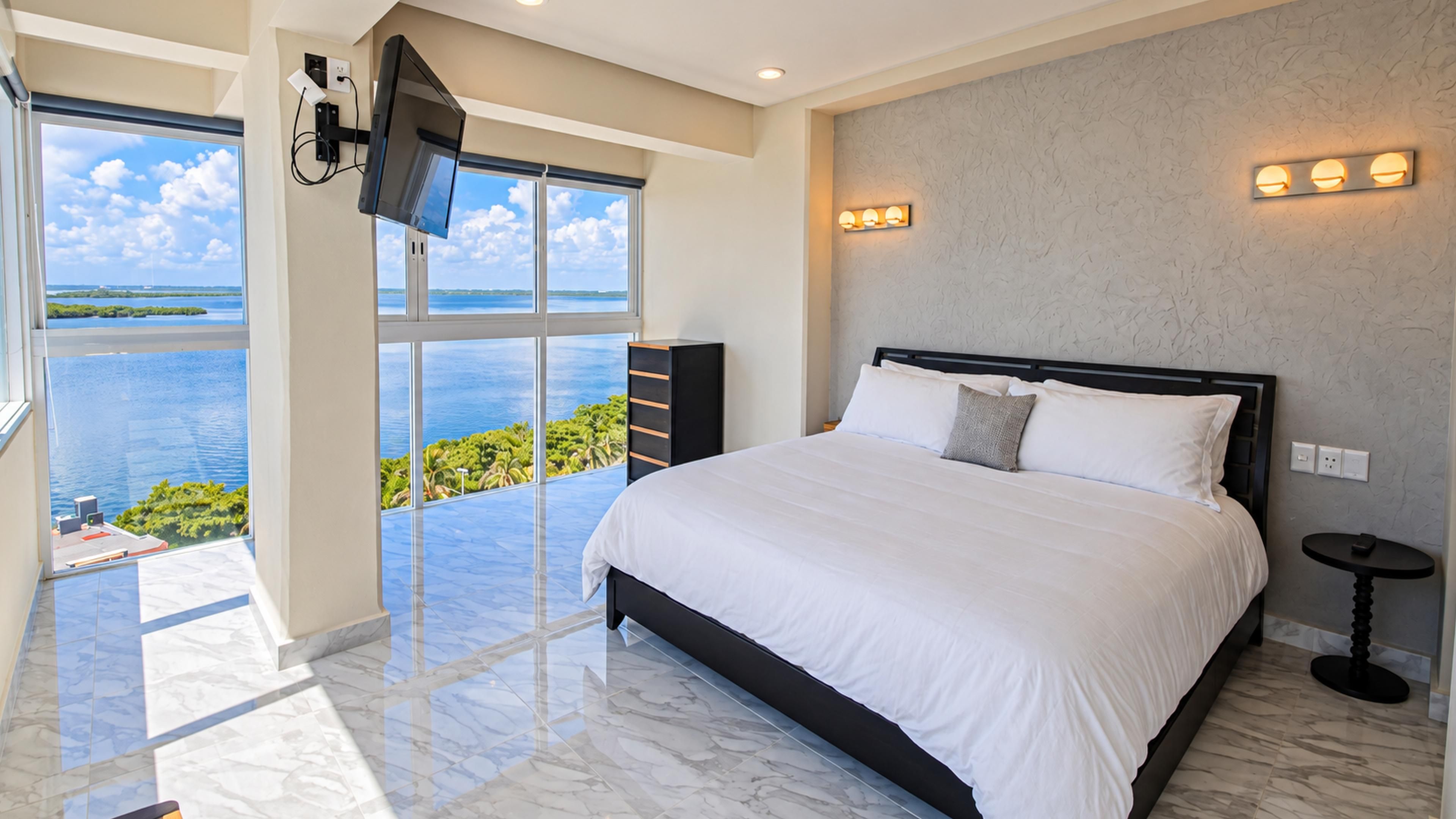 Primary bedroom with a king bed, expansive windows, Caribbean and Nichupté Lagoon views.