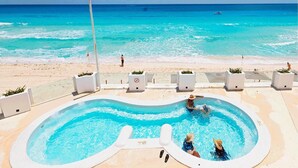 Una piscina con vista al océano, rodeada de sillas de playa y macetas.