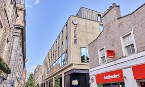Un edificio moderno con un llamativo letrero de 'Premier Inn', un letrero de 'Ladbrokes' y un letrero de 'No Entry'.