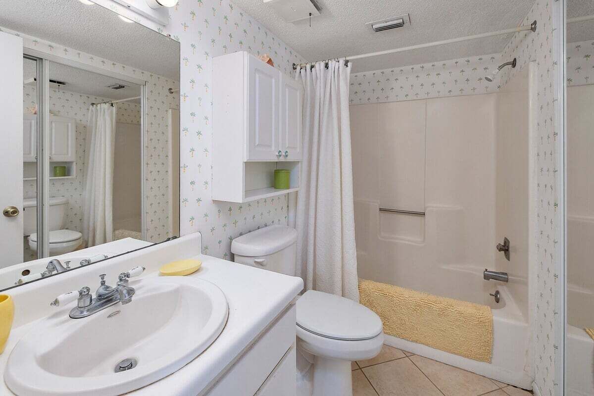A bathroom with a white sink, toilet, and shower area.