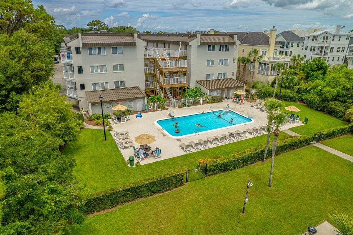 A multi-story residential building with a swimming pool, outdoor seating, and a well-maintained lawn.