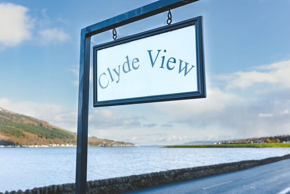 Letrero que dice 'Clyde View' con vista a un cuerpo de agua y colinas.