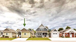 Un hilera de casas unifamiliares con un estilo arquitectónico uniforme, un camino central y un cielo nublado.