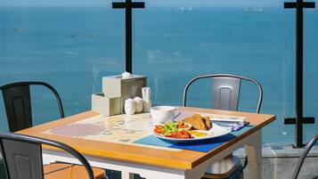 A table with breakfast, a cup, and a view of the sea.