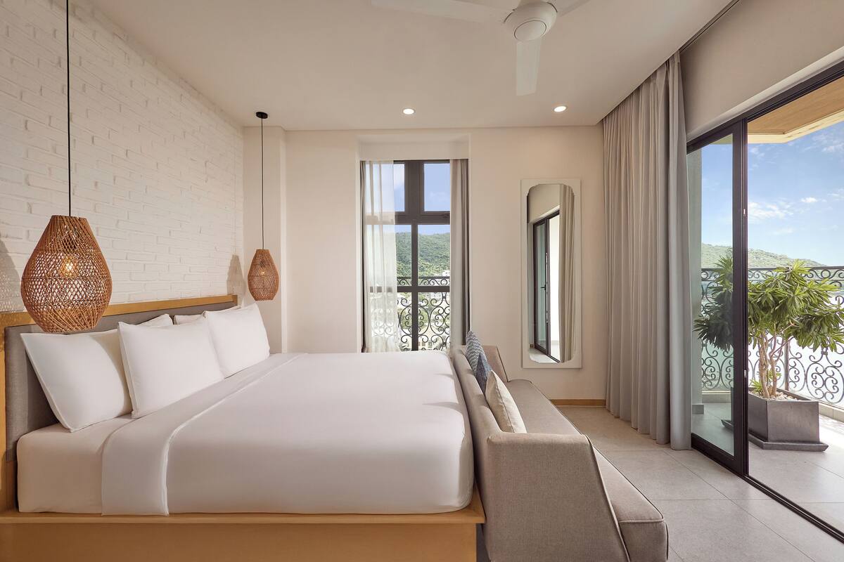 Een moderne slaapkamer met een groot bed, uitzicht op het groen en een balkon met een hekwerk.