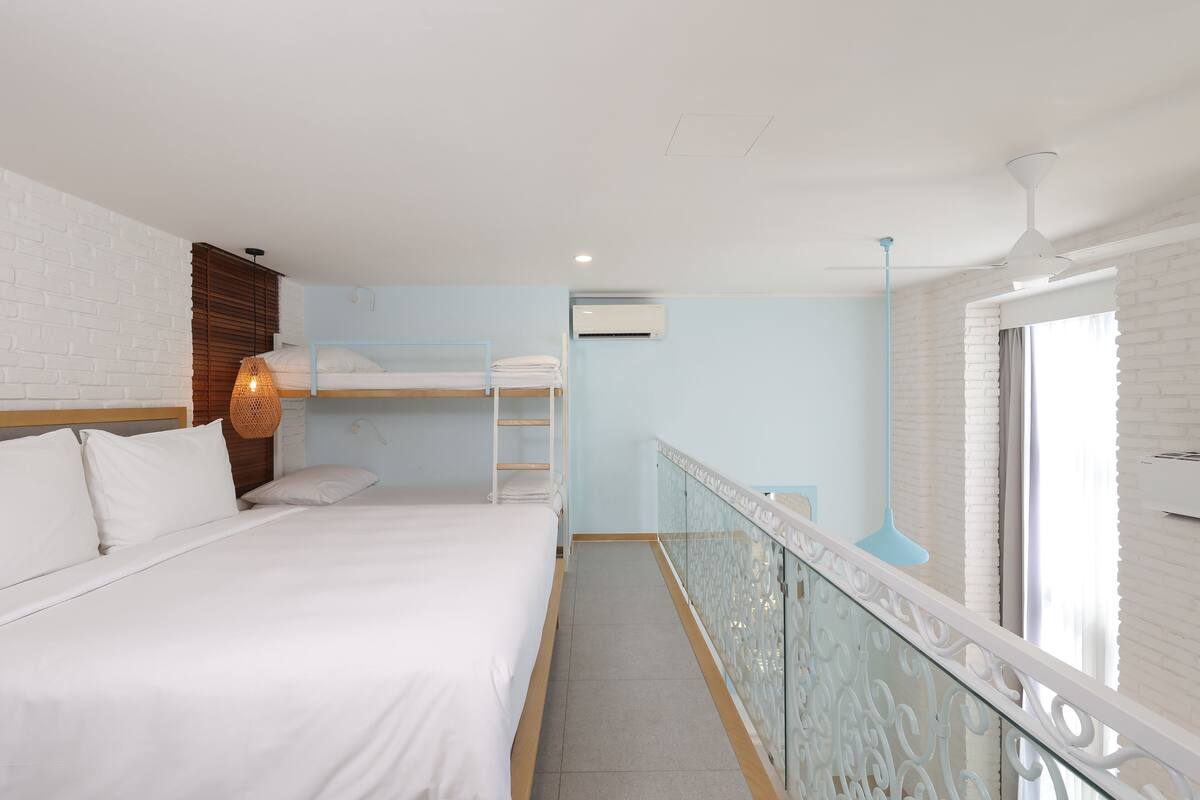 Een hotelkamer met een stapelbed, een balkon met een leuning en een airconditioning op de muur.