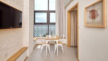 A modern kitchen with white brick walls, a large window with a view, and a dining area with white chairs and a wooden table.