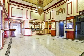 A spacious lobby with a marble floor, a reception desk, and a chandelier.