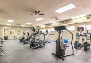 Une salle de sport équipée de tapis de course, de vélos elliptiques et de matériel de musculation.