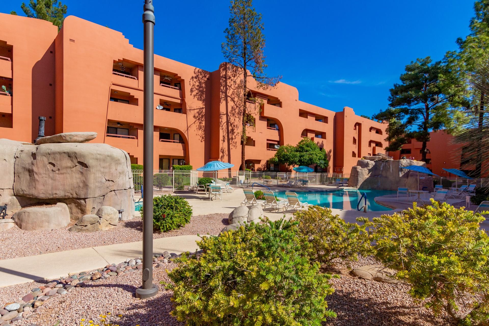 A resort with a swimming pool, outdoor seating, and a rock garden.