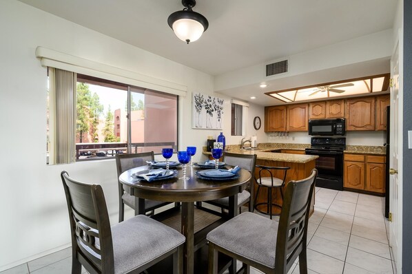 A modern kitchen with wooden cabinets, a built-in microwave, and a dining area with a round table and chairs.