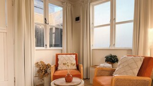 Une pièce avec deux fauteuils orange, une table basse ronde en bois et une plante en pot.