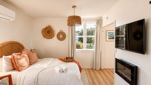 Une chambre à coucher avec un lit, une télévision, une cheminée et une fenêtre avec des rideaux.