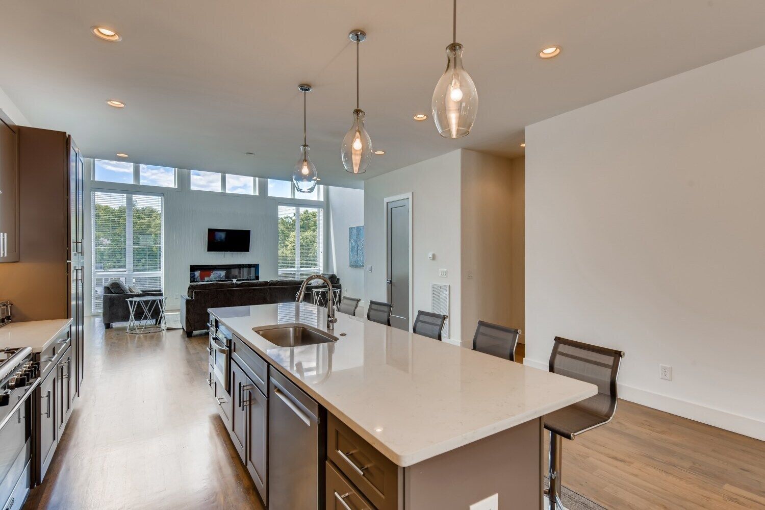 A modern kitchen with a large island, stainless steel appliances, and pendant lighting.