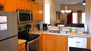 Una cucina con mobili in legno, elettrodomestici in acciaio inossidabile, lavastoviglie e macchina del caffè.