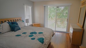 Una camera da letto con un letto, un comodino, una cassettiera e una porta scorrevole con accesso a un balcone.