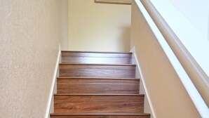 Una scala in legno con ringhiera bianca e pareti beige.