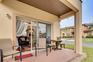 A covered patio with outdoor furniture, including a sofa, chairs, and a table.