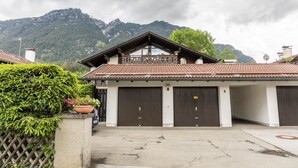 Um edifício com duas grandes portas de garagem, uma varanda e montanhas ao fundo.